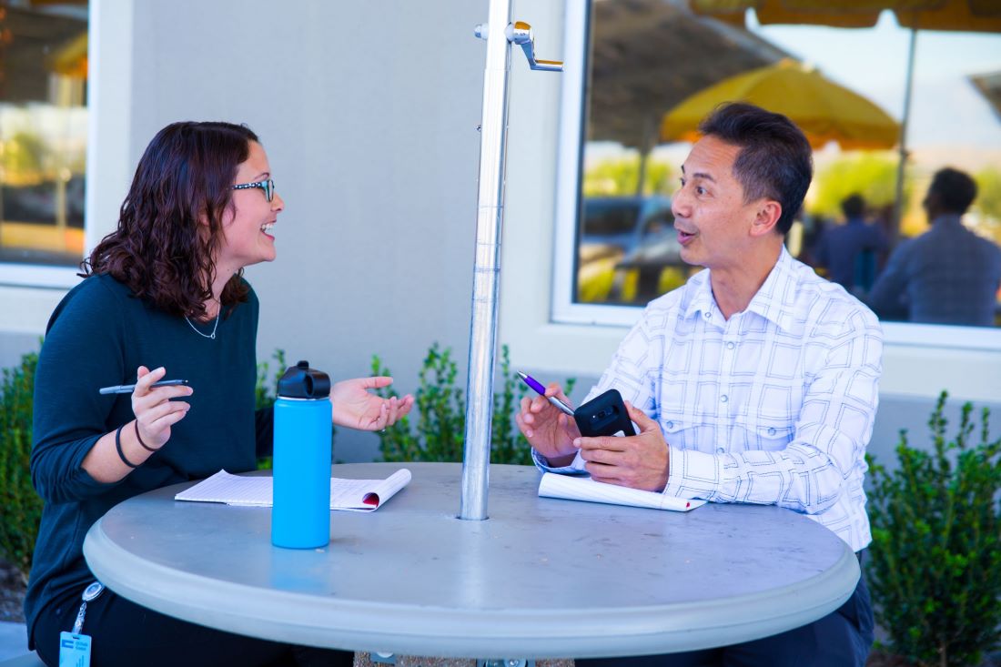 Two UCPath employees chatting outside at a table